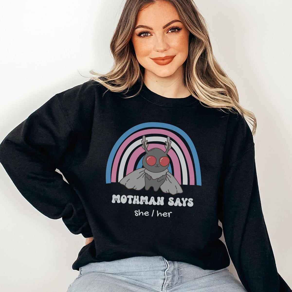 Person wearing a black custom transgender sweatshirt with mothman and text against a white background