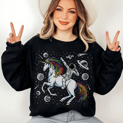 Person wearing a black sweatshirt with a rainbow lgbtq unicorn and astronaut design, making peace signs.