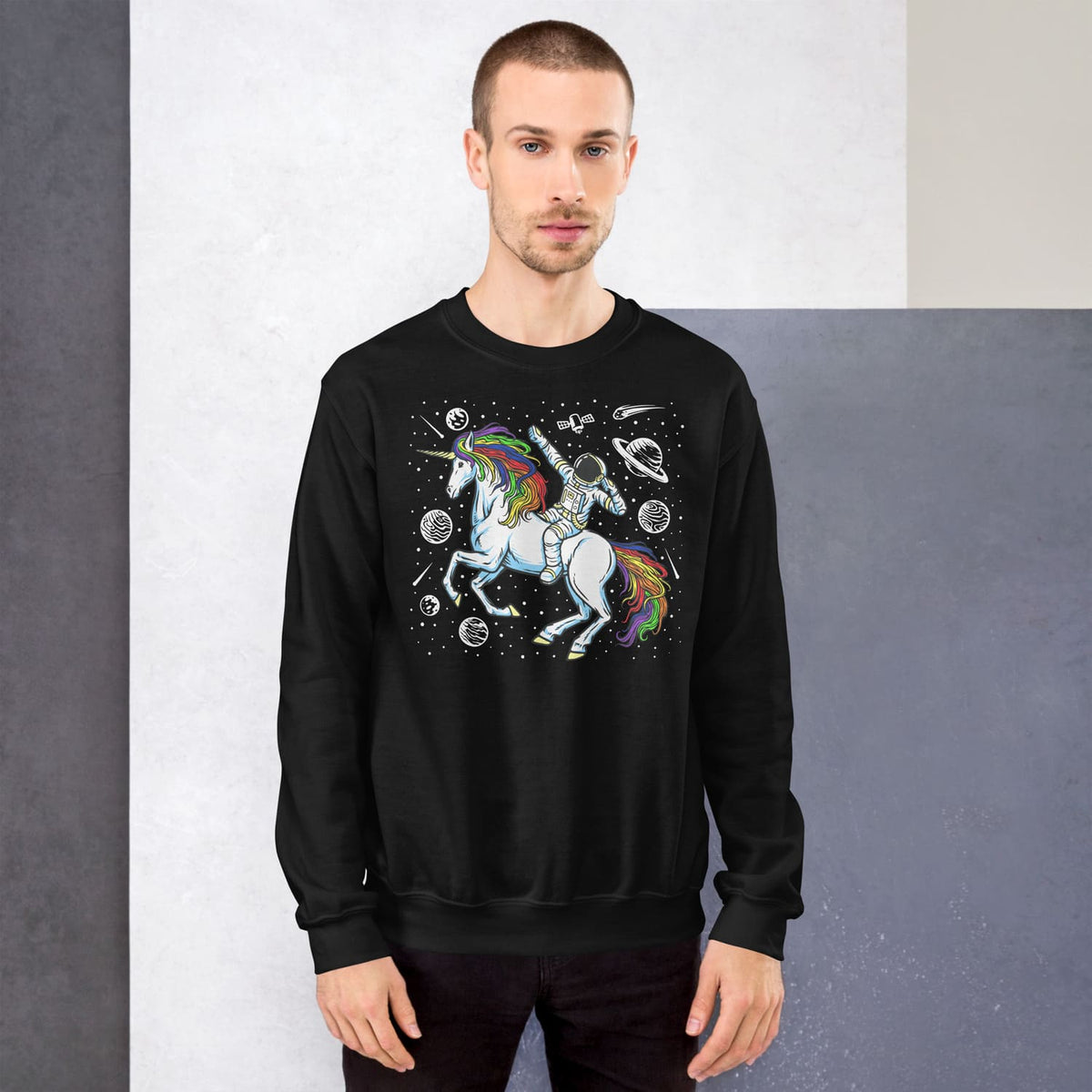 Man wearing a black sweatshirt with a discreet lgbtq pride unicorn design against a gray background