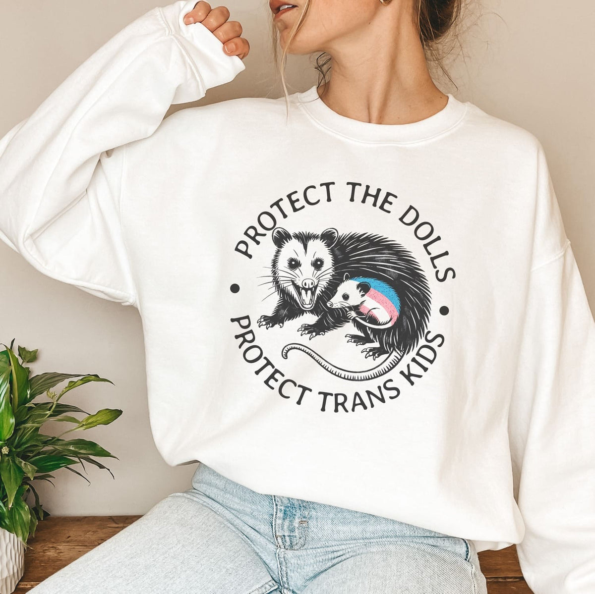 Person wearing a white 'protect trans kids' sweatshirt with a graphic design and text.