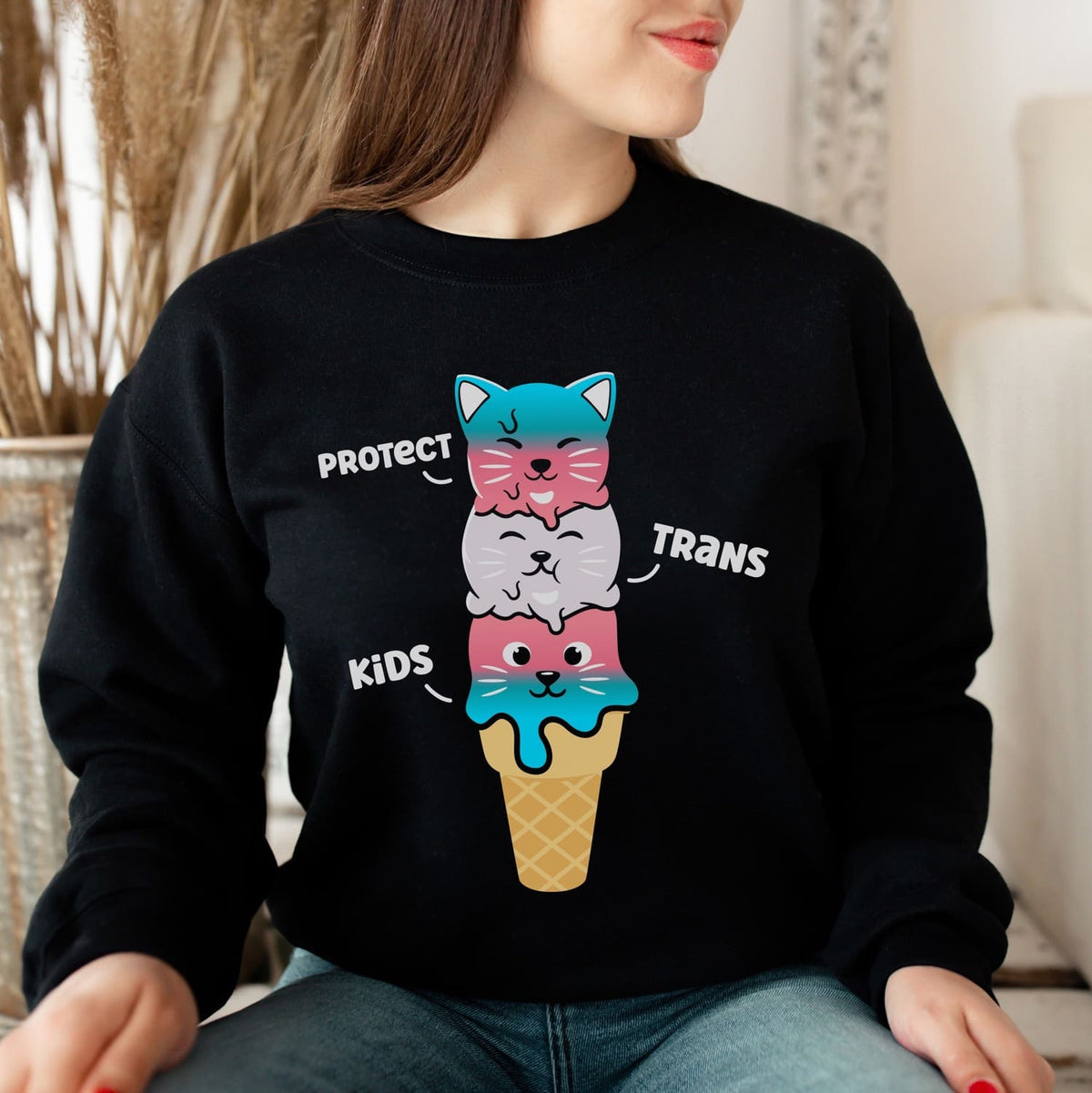 Transgender woman wearing a cute sweatshirt with a colorful graphic and text protect trans kids