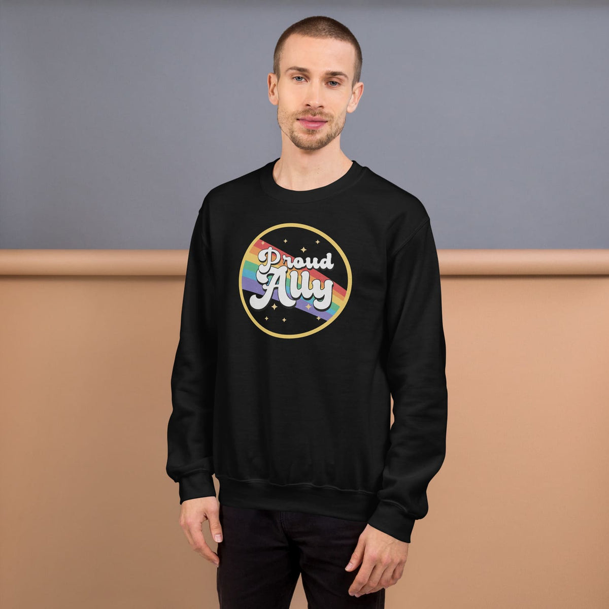 Man wearing a black sweatshirt with a colorful 'Proud Ally' graphic on a brown and gray background