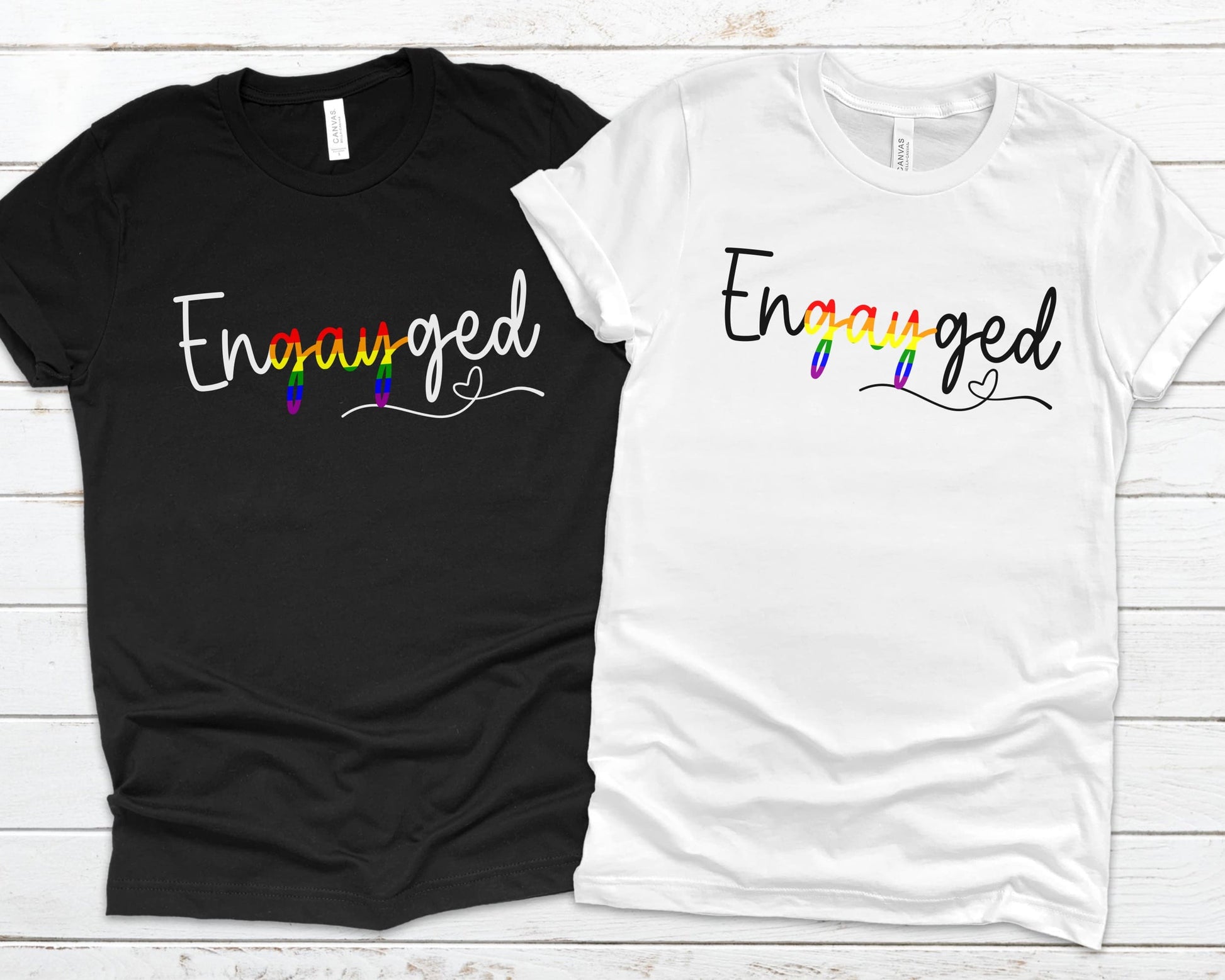 Queer engagement matching t-shirts with 'Engayged' text on a wooden surface