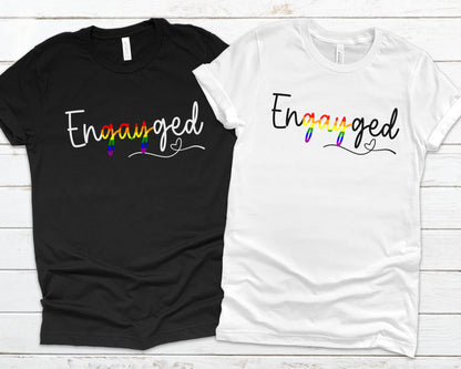 Queer engagement matching t-shirts with 'Engayged' text on a wooden surface