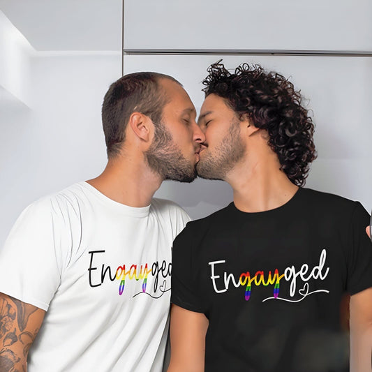 Two gay men kissing, wearing 'Engayged' matching shirts with rainbow text.