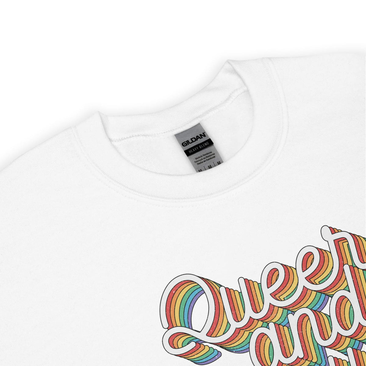 Detail of pride sweatshirt with rainbow-colored 'Queer & proud' text on a white background