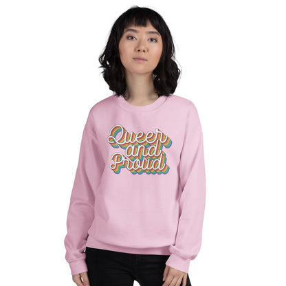 Person wearing a pink pride sweatshirt with 'Queer and Proud' rainbow text on a white background