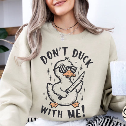 Person wearing a beige funny  sweatshirt with a graphic design and text 'Don't Duck With Me!'