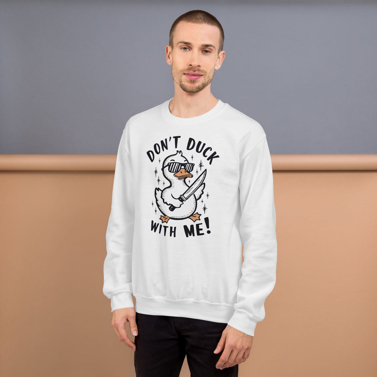 Man wearing a white funny sweatshirt with a duck graphic design and text against a plain background