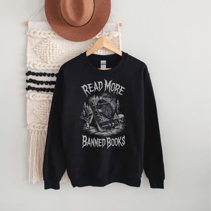 Black sweatshirt with 'Read More Banned Books' text and graphic on a hanger against a white wall.