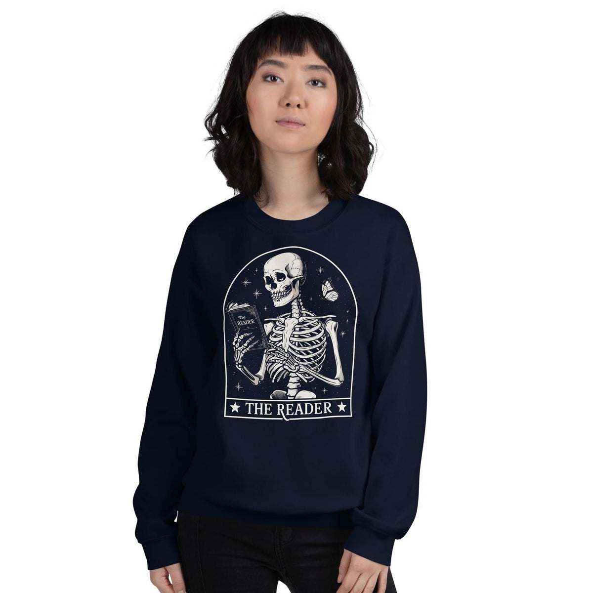 Person wearing a navy blue bookish sweatshirt with a skeleton design and 'The Reader' text on a white background