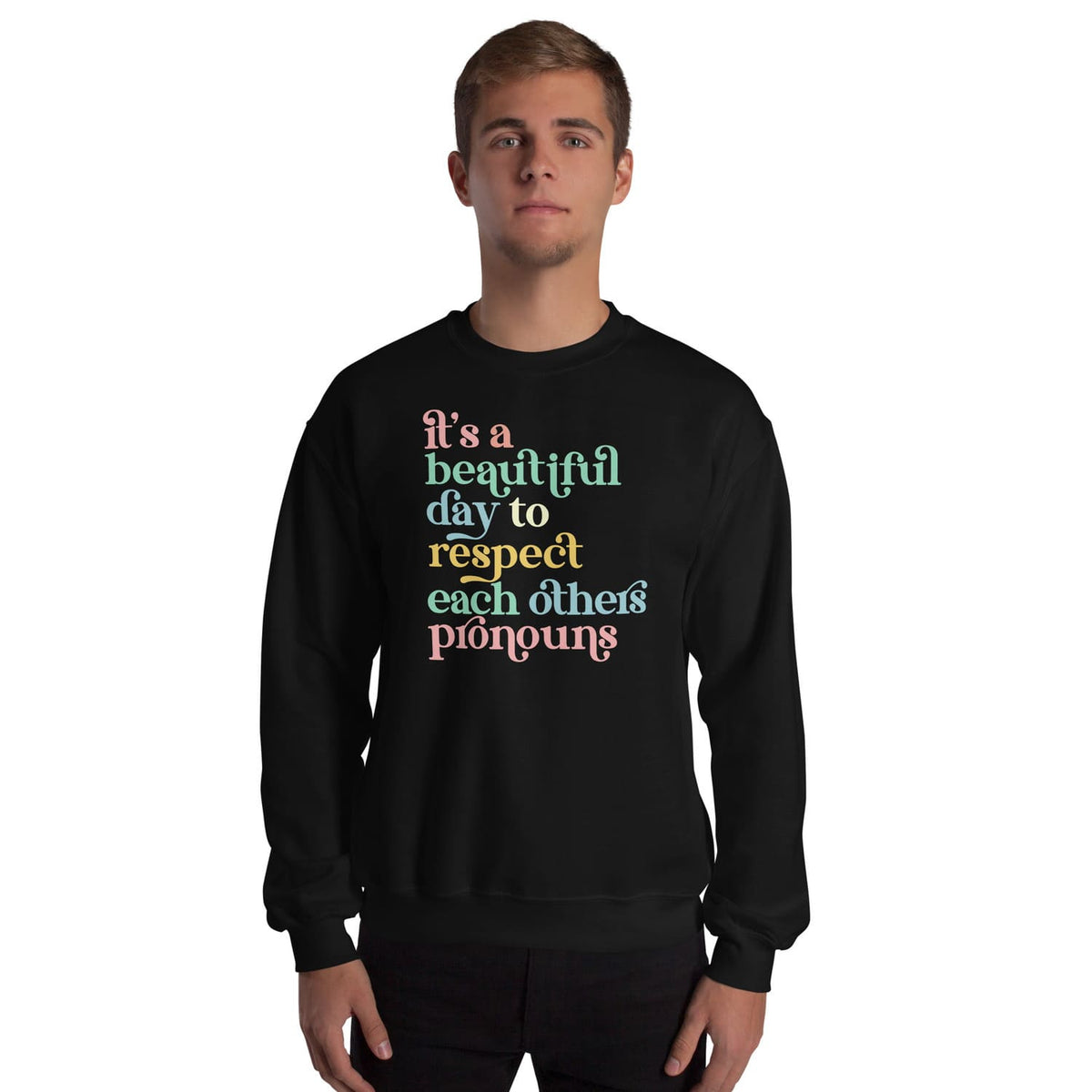 Person wearing a black pronouns sweatshirt with colorful text on a white background