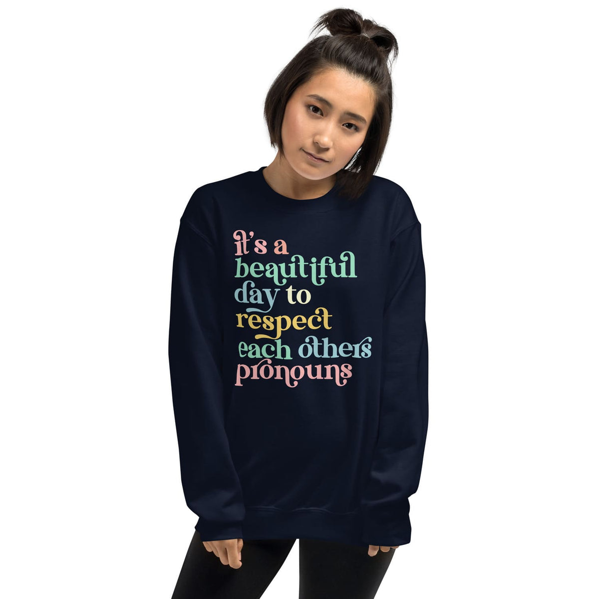 Person wearing a navy pronouns sweatshirt with colorful text on a white background