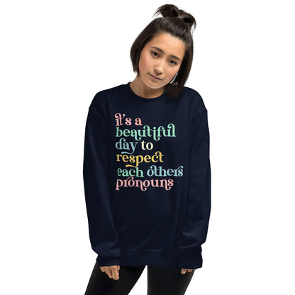 Person wearing a navy pronouns sweatshirt with colorful text on a white background