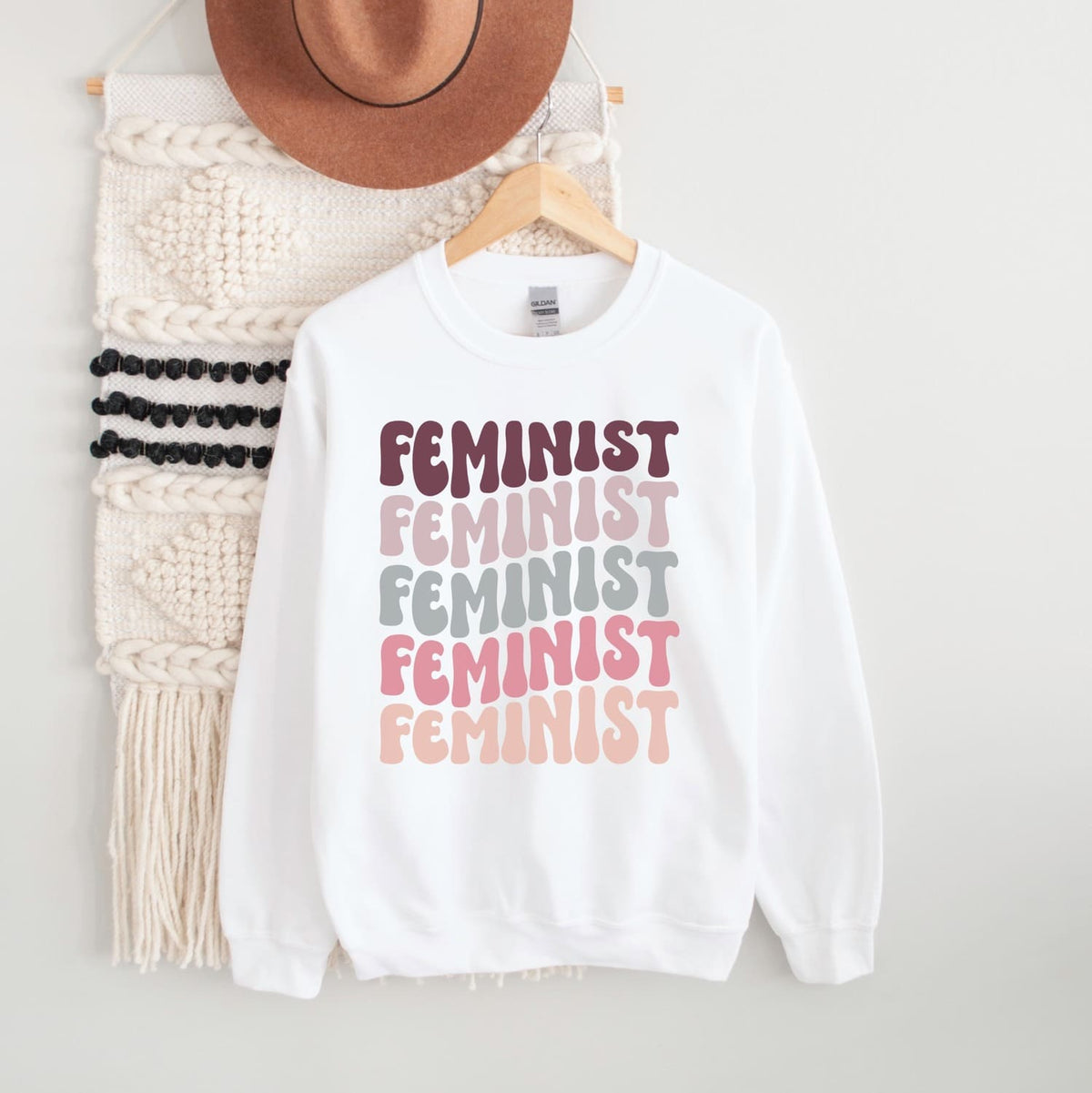 White sweatshirt with 'Feminist' text in different colors on a white background