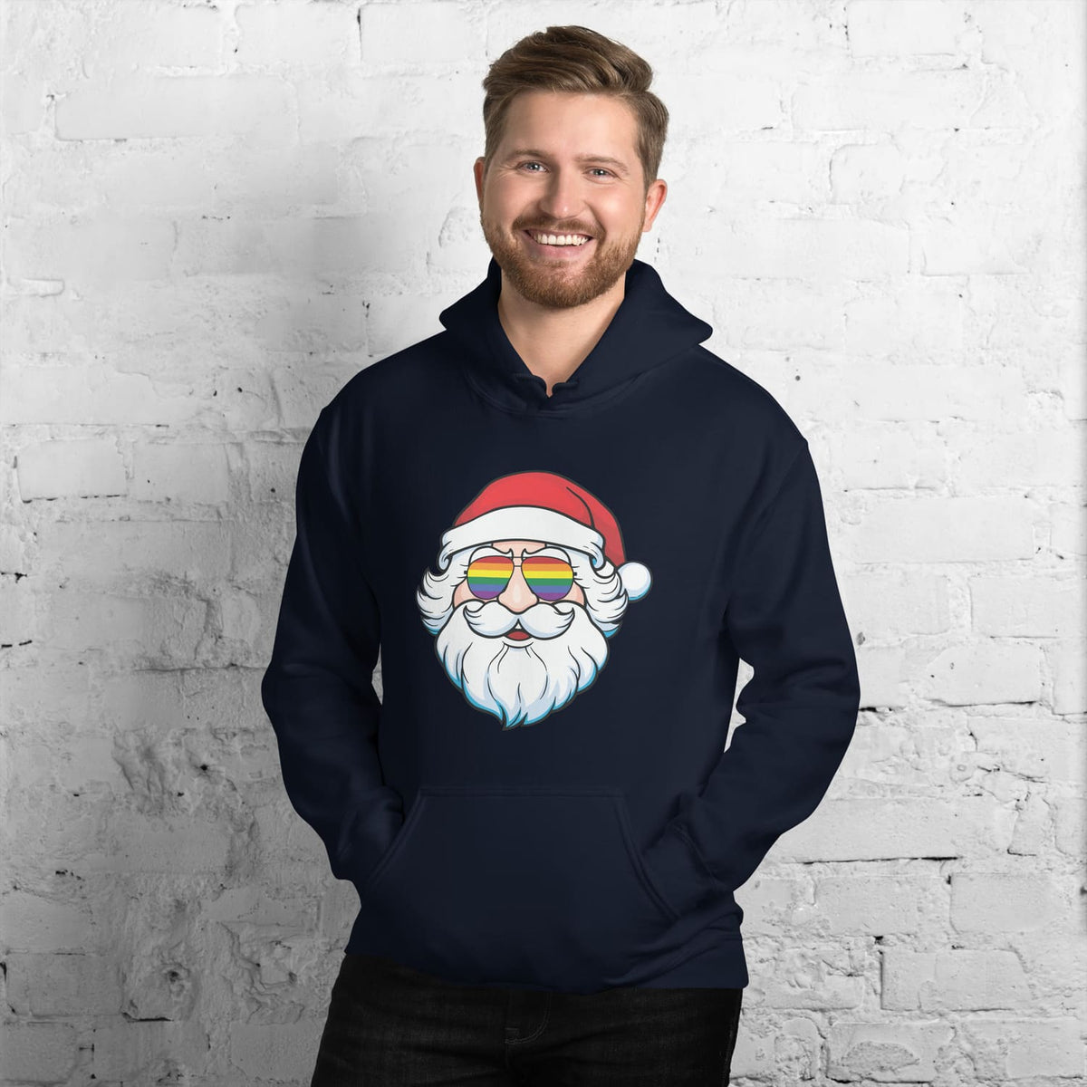 Man wearing a navy hoodie with a Santa Claus wearing lgbtq glasses design against a white brick wall