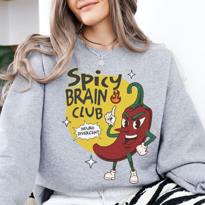 Person wearing a gray neurodivergent sweatshirt with a cartoon chili pepper and 'Spicy Brain Club' text design.