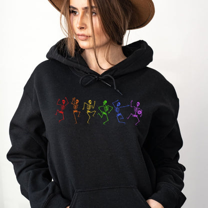 Person wearing a black hoodie with colorful lgbtq rainbow skeleton designs on a white background