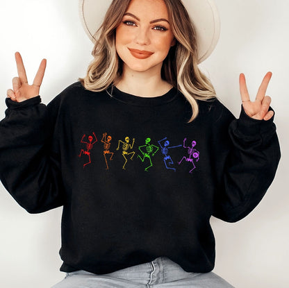 Person wearing a spooky sweatshirt with colorful pride skeleton designs and making peace signs.