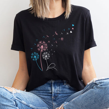 Person wearing a black t-shirt with colorful transgender dandelion graphic design.