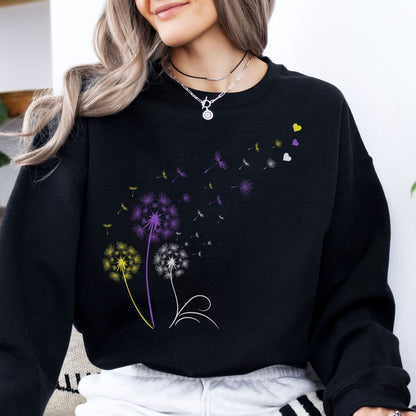 Person wearing a black enby pride sweatshirt with colorful dandelion designs.