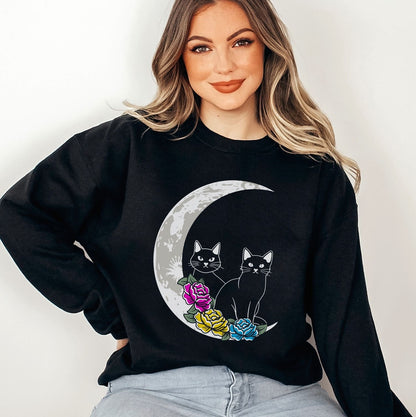 Person wearing a black pan pride sweatshirt with a moon and cat design on a plain background