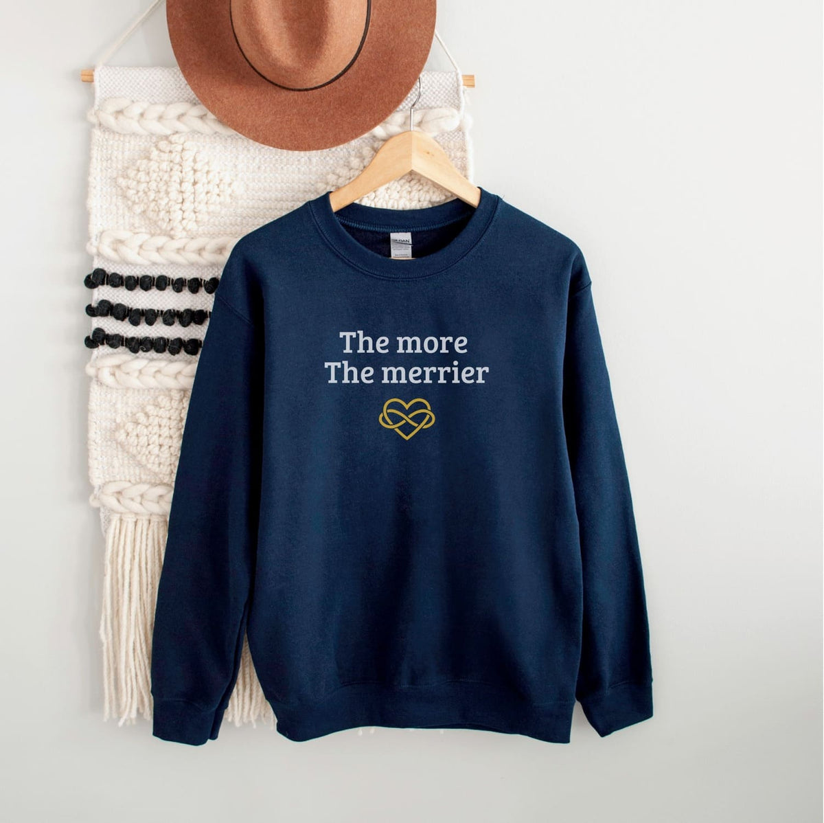 Navy blue polyamory weatshirt with 'The more The merrier' text and heart design on a white background