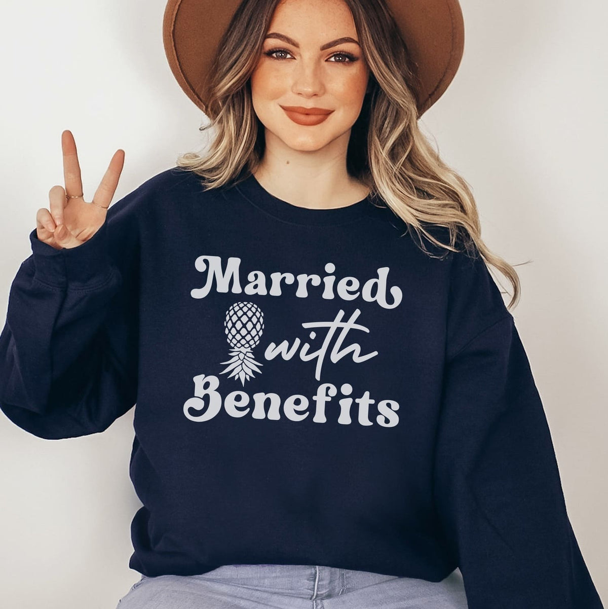 Woman wearing a navy swingers sweatshirt with 'Married with Benefits' text and a pineapple graphic.
