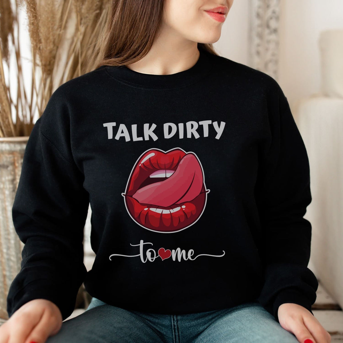 Person wearing a black sweatshirt with a graphic of lips and text 'Talk Dirty to Me' indoors.