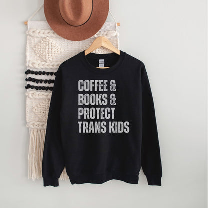 Black sweatshirt with text 'COFFEE & BOOKS & PROTECT TRANS KIDS' on a hanger against a white wall.