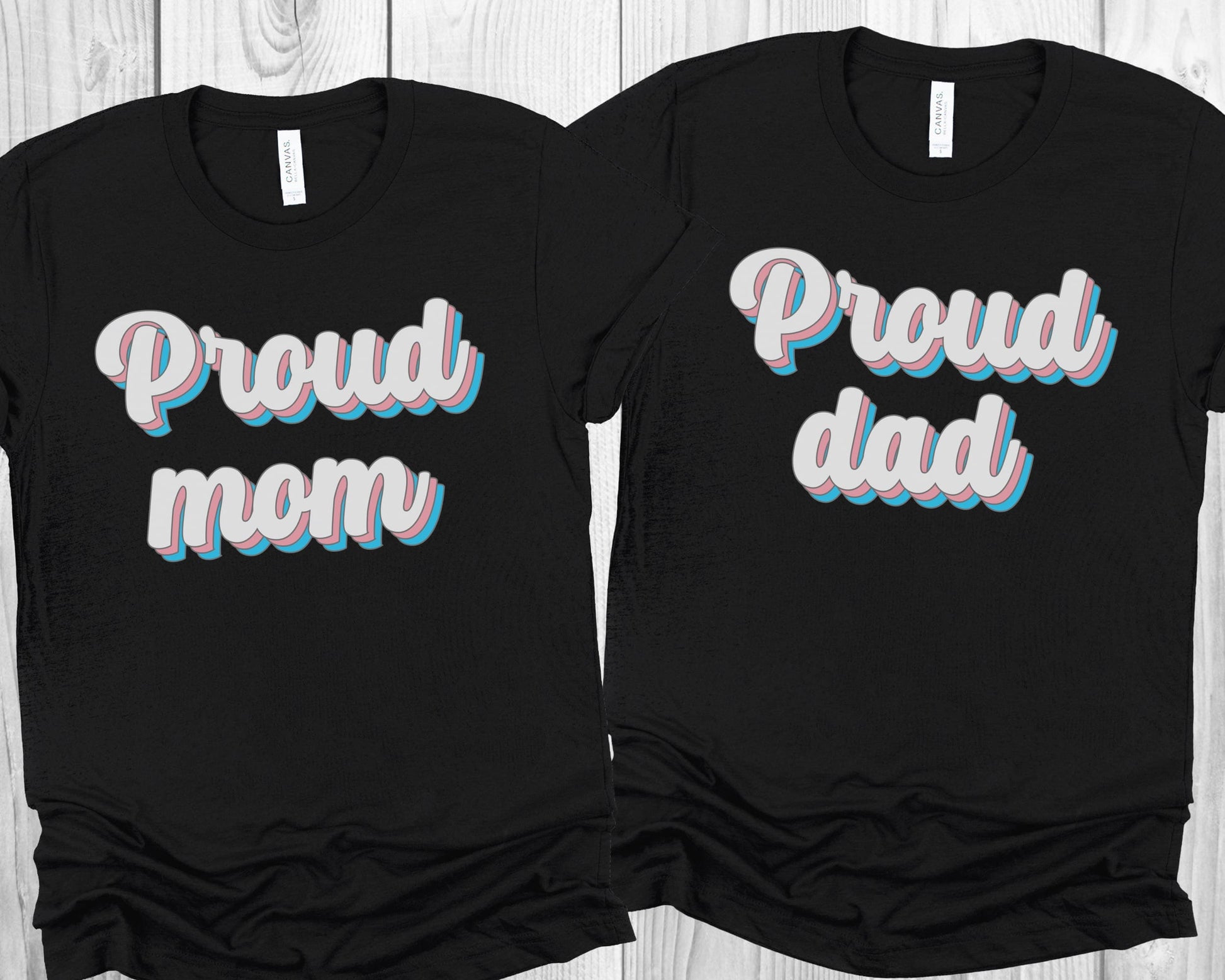 matching transgender  t-shirts with 'Proud mom' and 'Proud dad' text on a wooden surface.