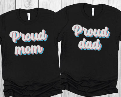 matching transgender  t-shirts with 'Proud mom' and 'Proud dad' text on a wooden surface.