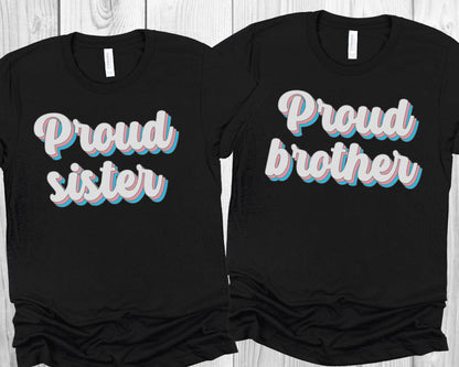 matching transgender t-shirts with 'Proud sister' and 'Proud brother' text on a wooden surface.