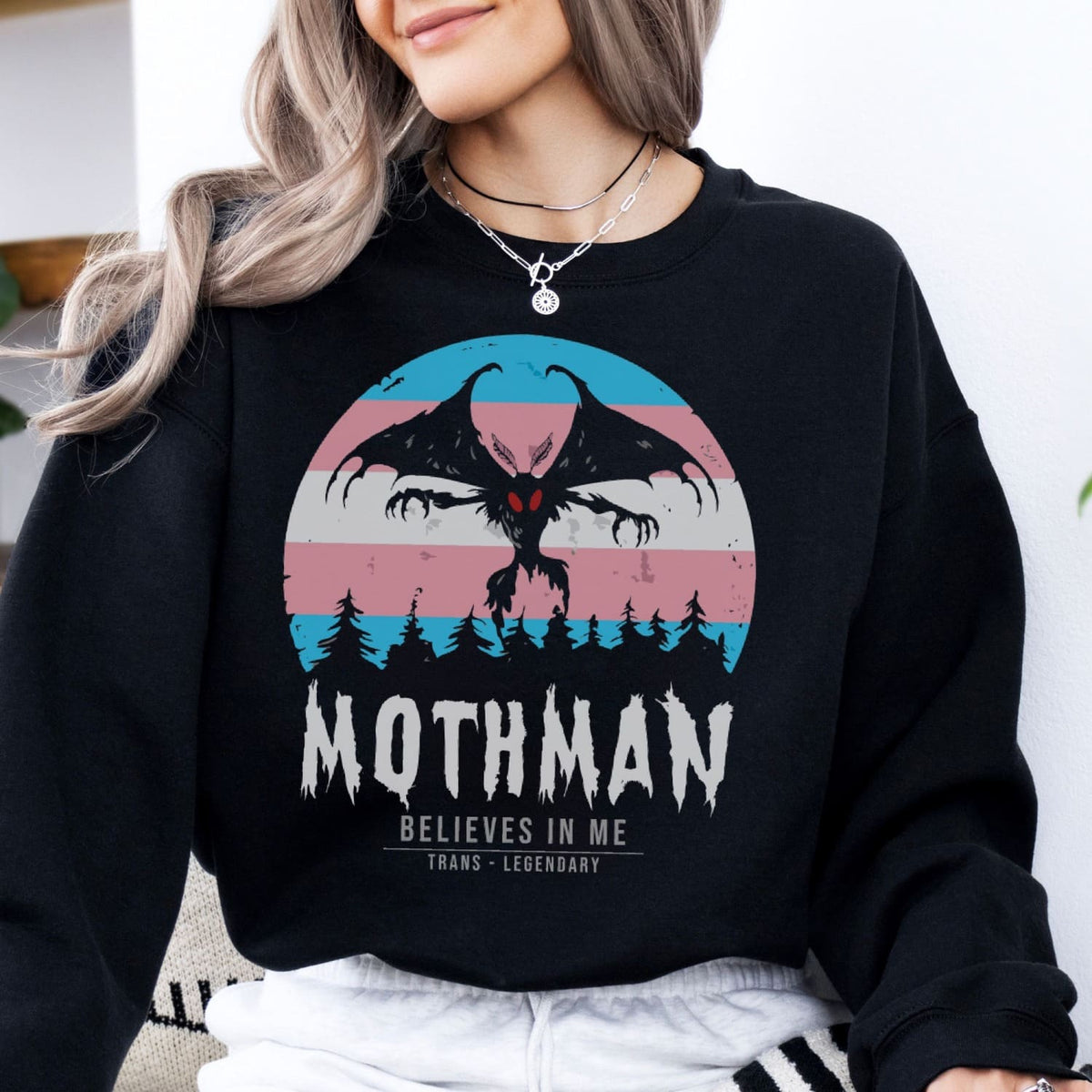 Person wearing a black transgender sweatshirt with Mothman graphic and text