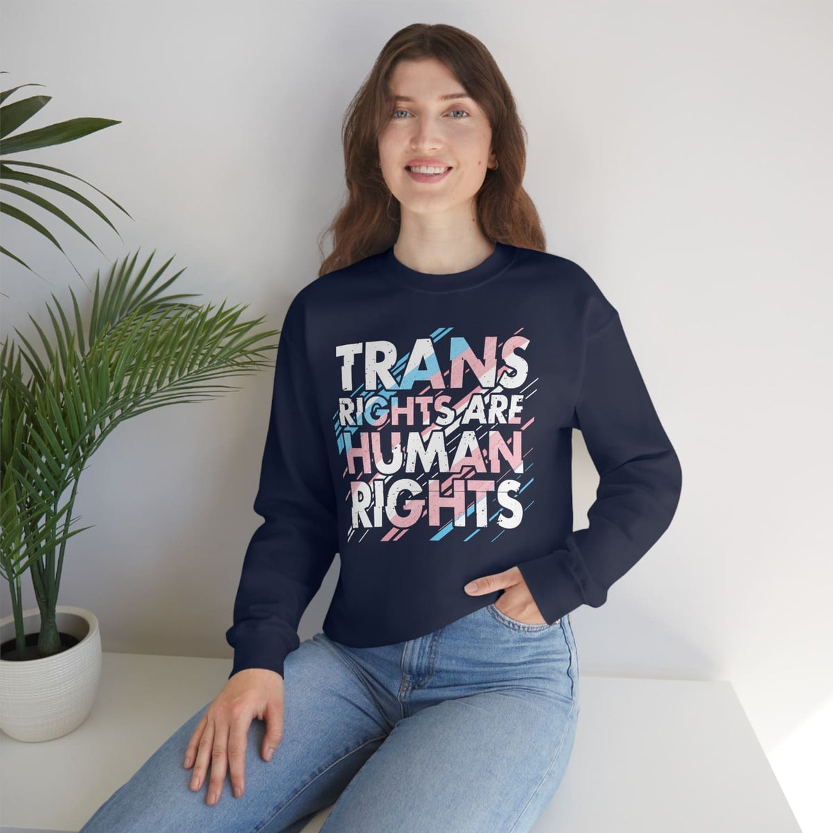 MTF transgender  wearing a navy blue sweatshirt with 'TRANS RIGHTS ARE HUMAN RIGHTS' text, sitting indoors.