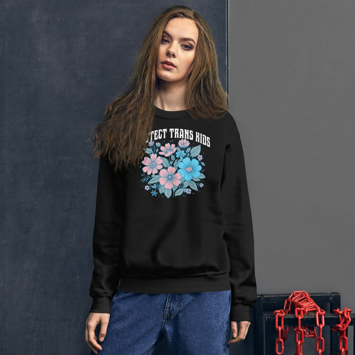 Person wearing a black transgender sweatshirt with floral design and text against a dark background