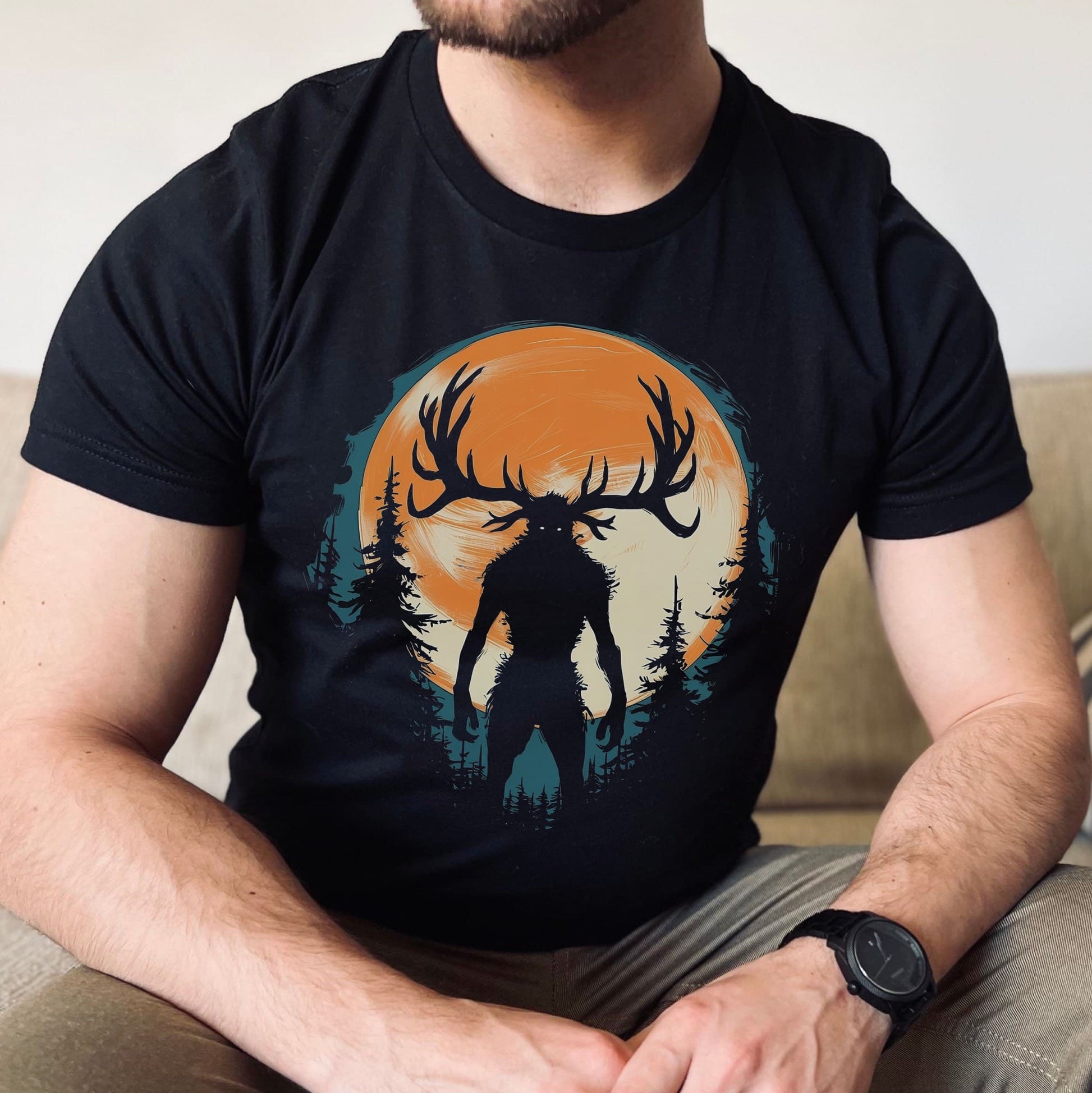 Person wearing a black t-shirt with a graphic of wendigo silhouette against an orange sky.