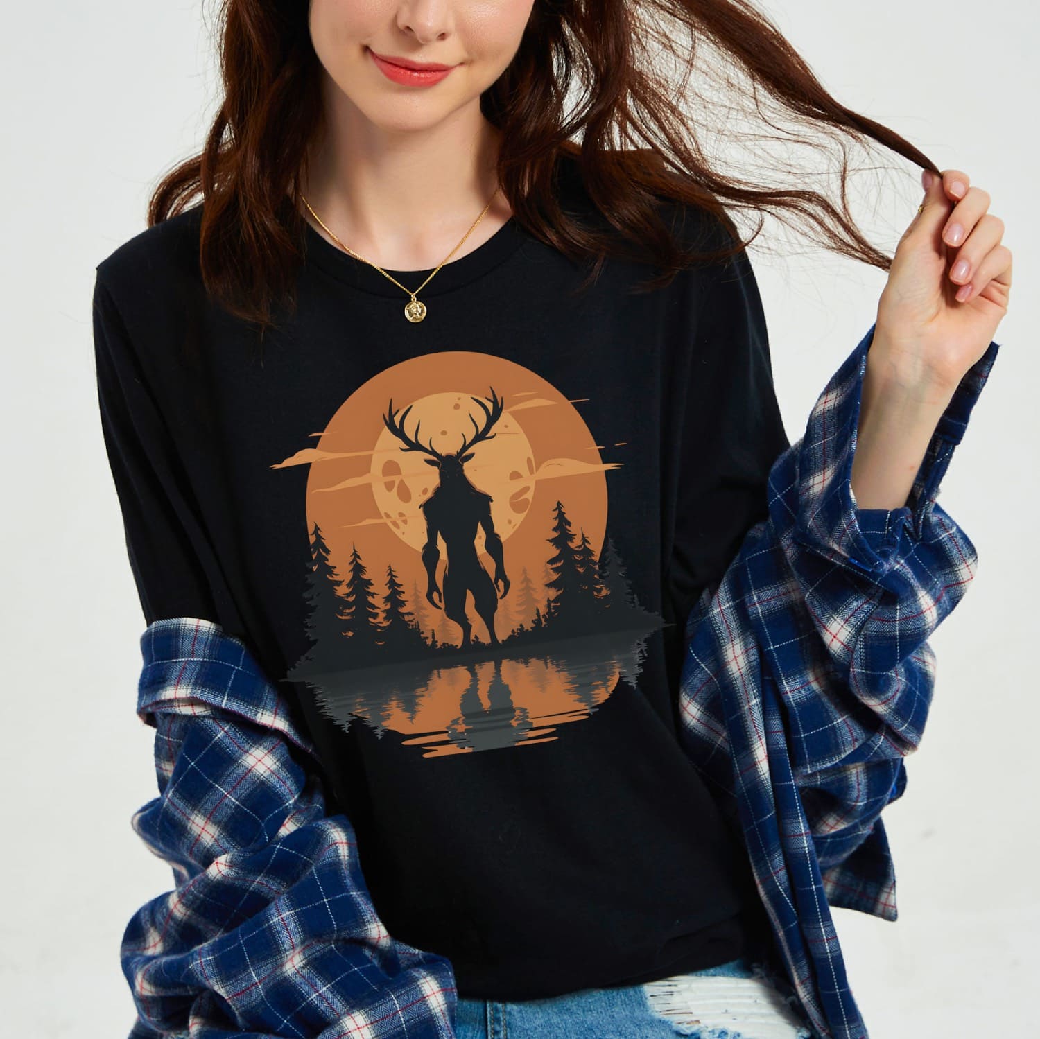 Person wearing a black sweatshirt with a wendigo and moon design, paired with a plaid shirt.