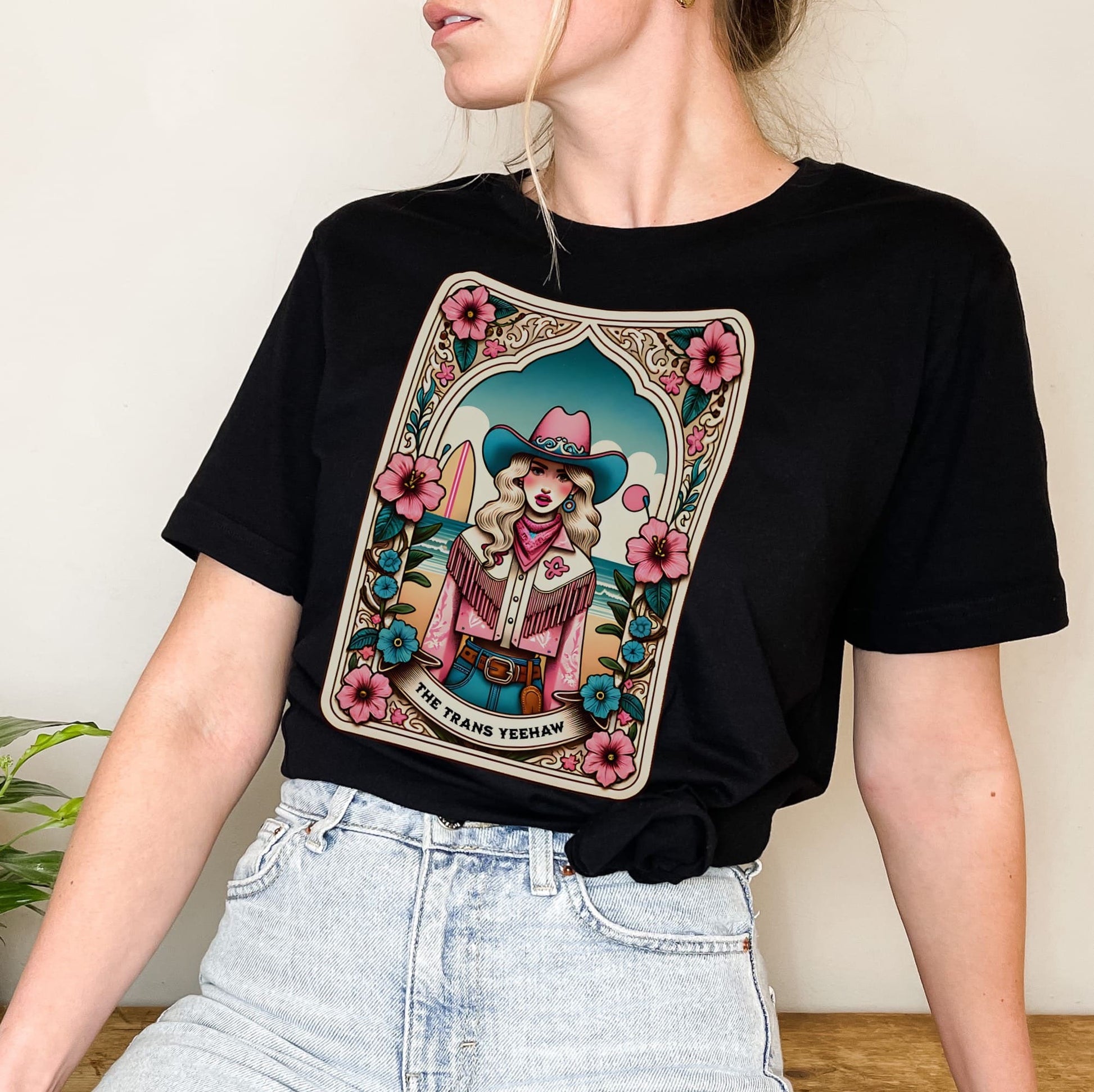 Person wearing a black t-shirt with a colorful graphic design of a tarot card featuring a woman in a cowboy hat: The Trans Yeehaw Tarot Card Shirt, Western MTF Subtle Transgender Pride Tee, Country Cowgirl T-Shirt, Rodeo Gift For Trans Daughter Sister