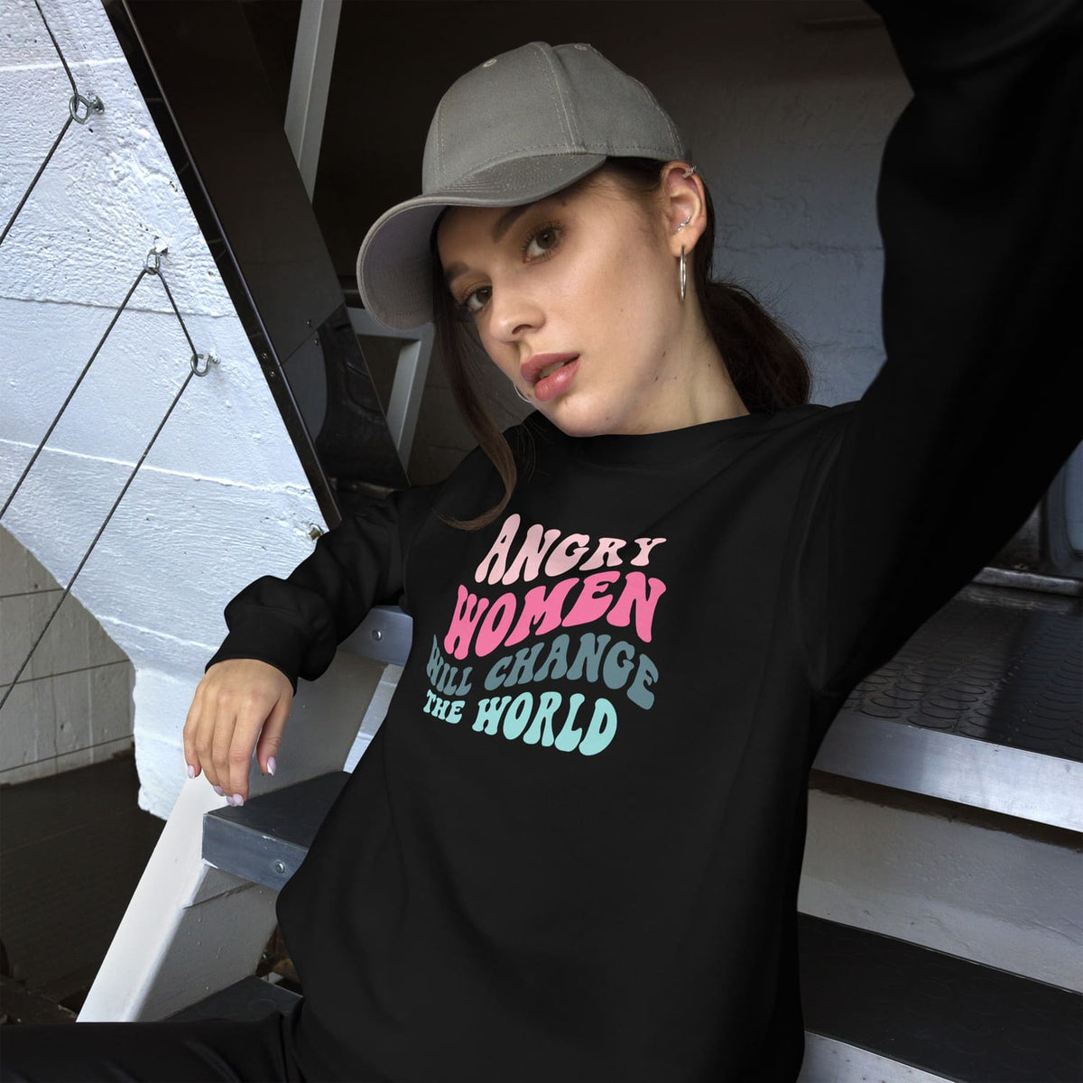 Person wearing a black feminist sweatshirt with a motivational quote, sitting on steps.