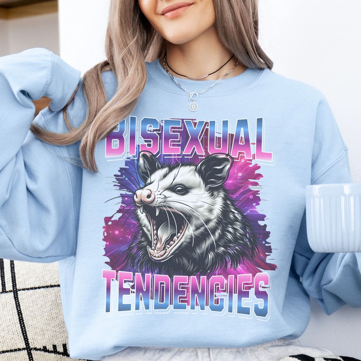 Person wearing a light blue sweatshirt with a graphic design of an opossum and text 'BISEXUAL TENDENCIES'.