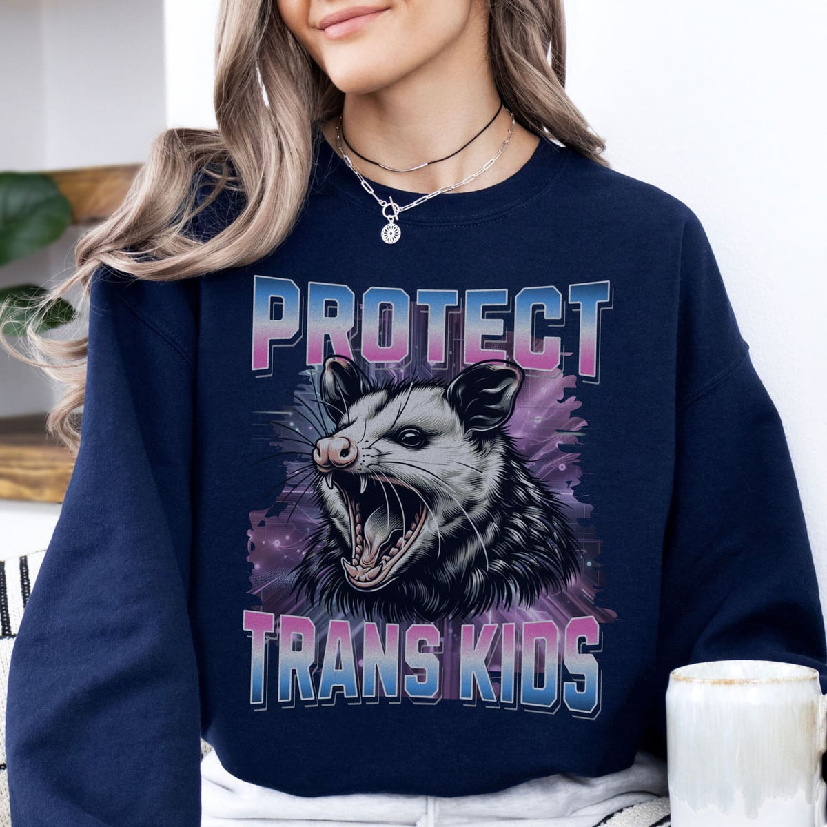 Person wearing a navy sweatshirt with an opossum graphic and text 'PROTECT TRANS KIDS'.