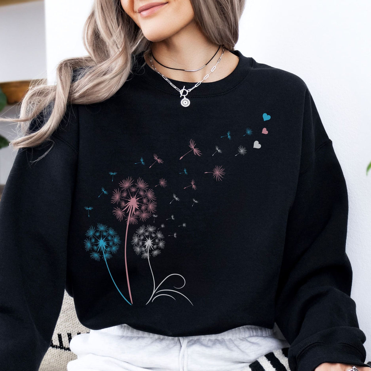 MTF woman wearing a black transgender sweatshirt with colorful dandelion designs.